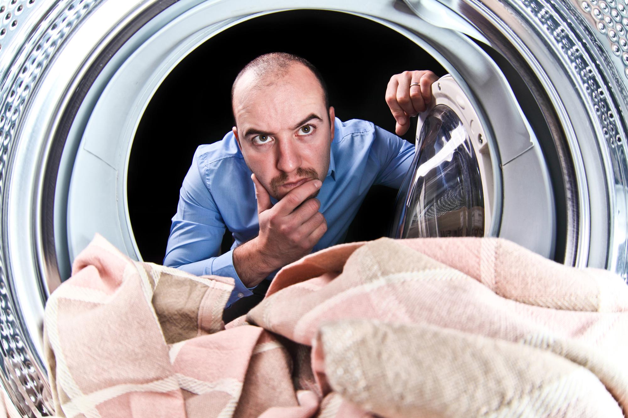 Porträt eines Mannes mit Blick auf eine Waschmaschine im Inneren